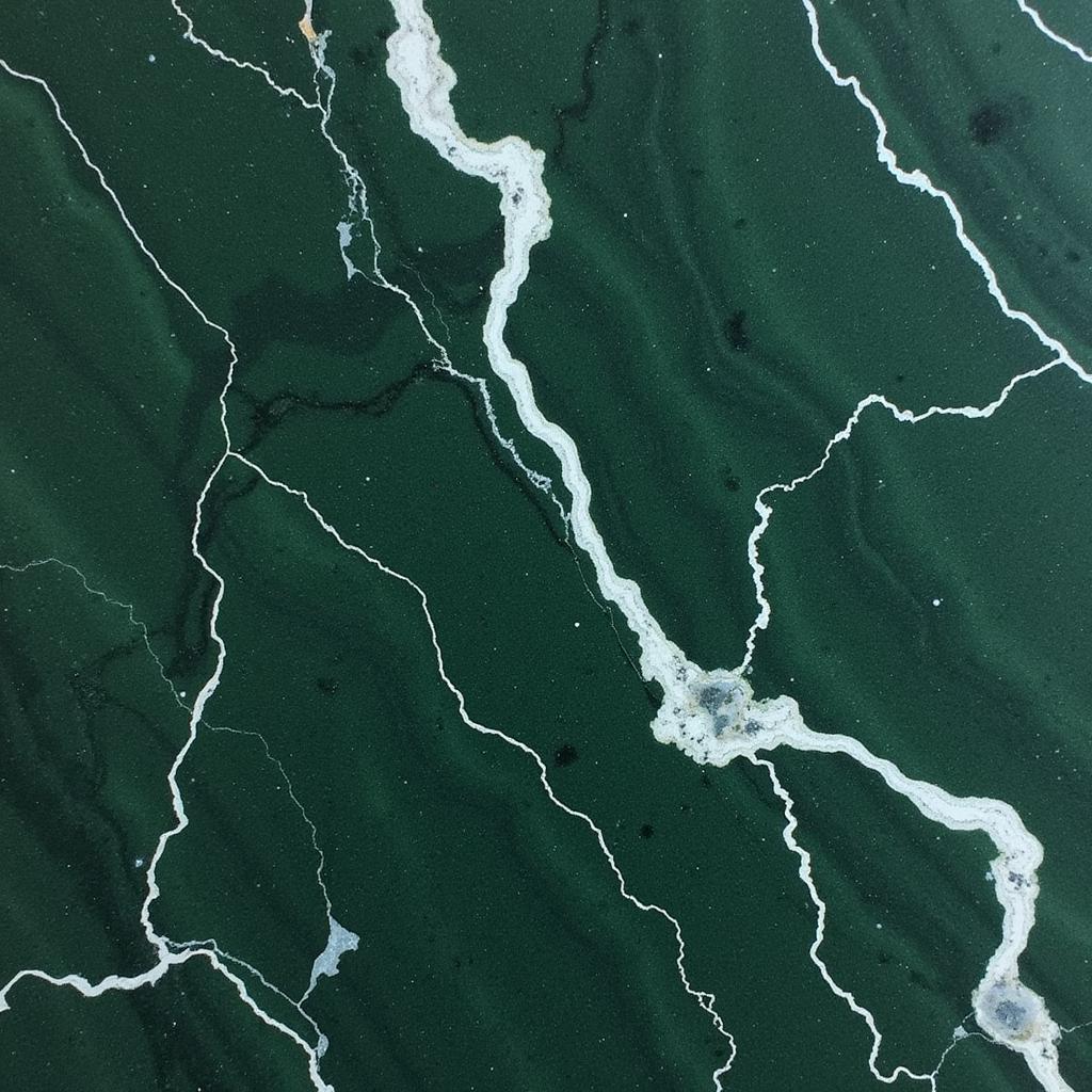 Close-up view of a polished Amazon marble slab showing vibrant green hues interspersed with white veining.